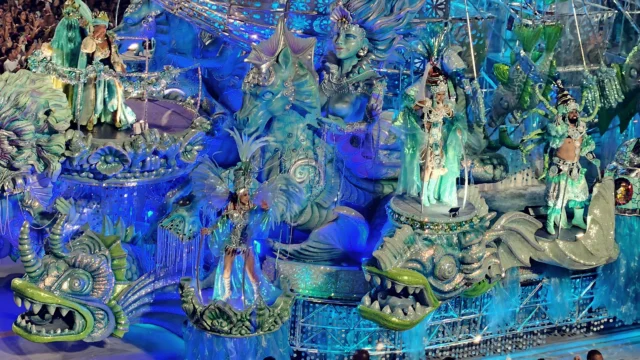 Carro alegórico iluminado em tons de azul desfila pela Sapucaí no Carnaval do Rio de Janeiro em 2025