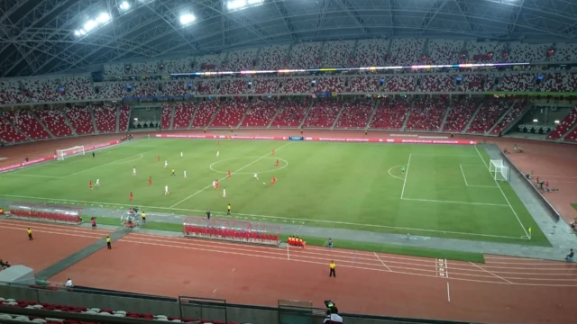 Campo e arquibancadas do Estádio Nacional de Singapura durante uma partida noturna.
