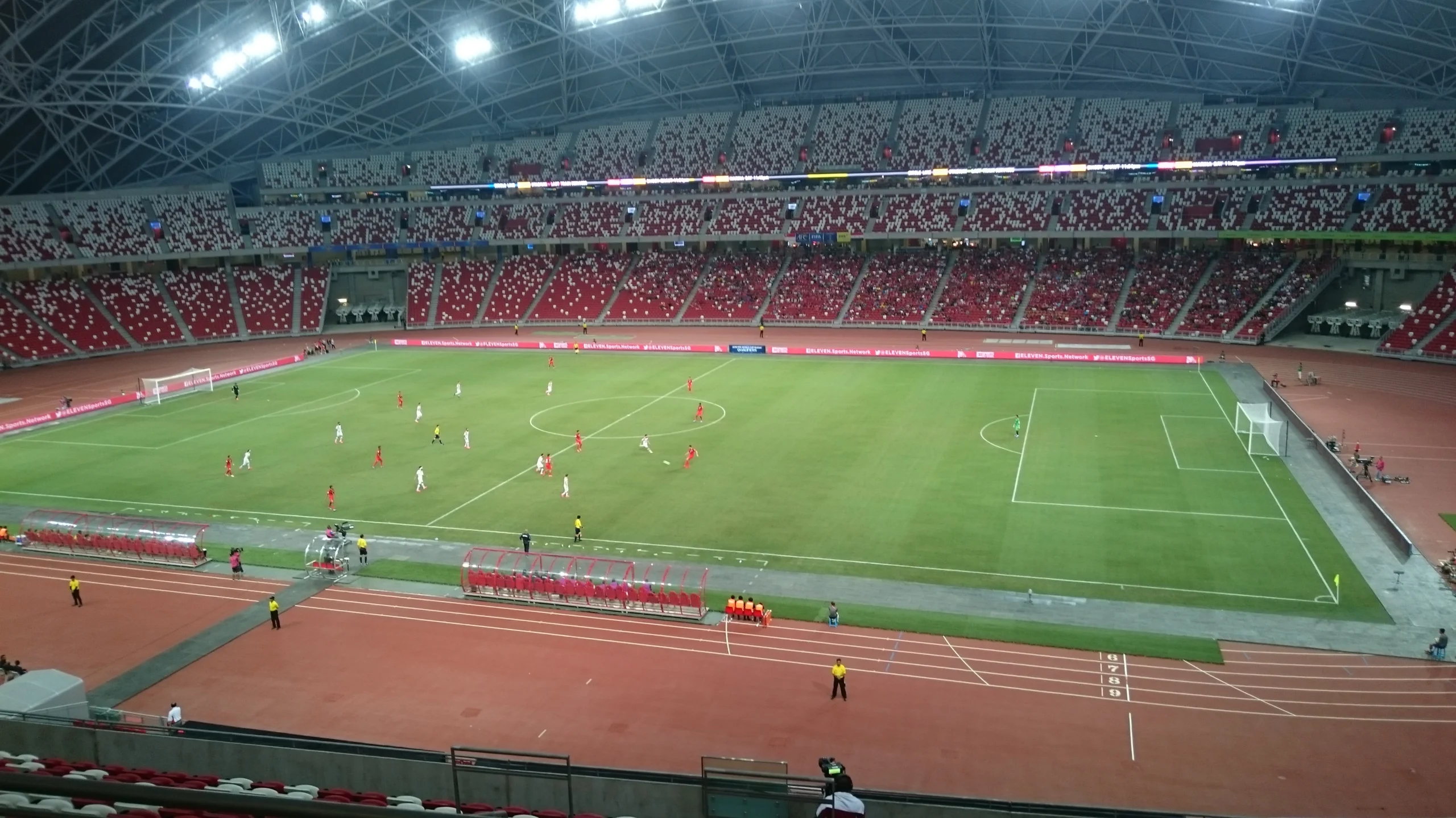 Campo e arquibancadas do Estádio Nacional de Singapura durante uma partida noturna.