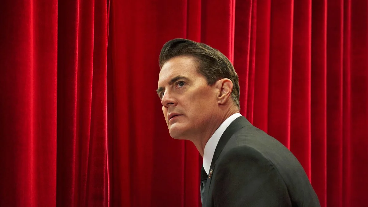 Agente Dale Cooper diante das cortinas vermelhas da Sala Vermelha na série Twin Peaks
