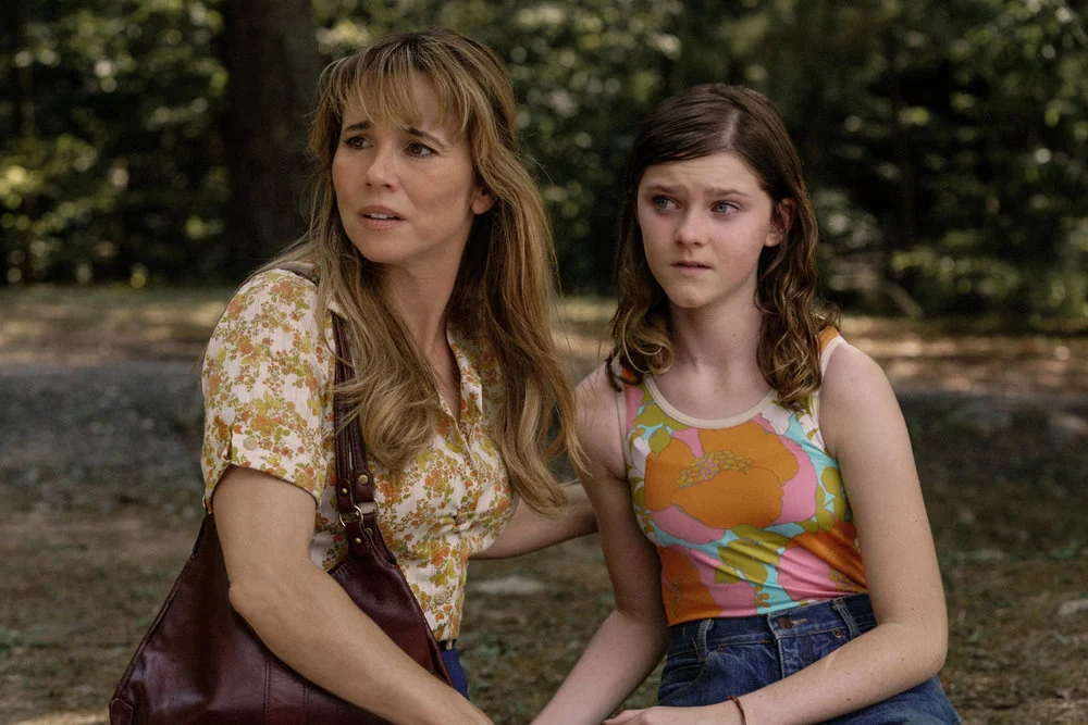 Linda Cardellini como Pamela Voorhees ao lado de Grace, interpretada por Gwendolyn Sundstrom, em uma cena ao ar livre de Crystal Lake.