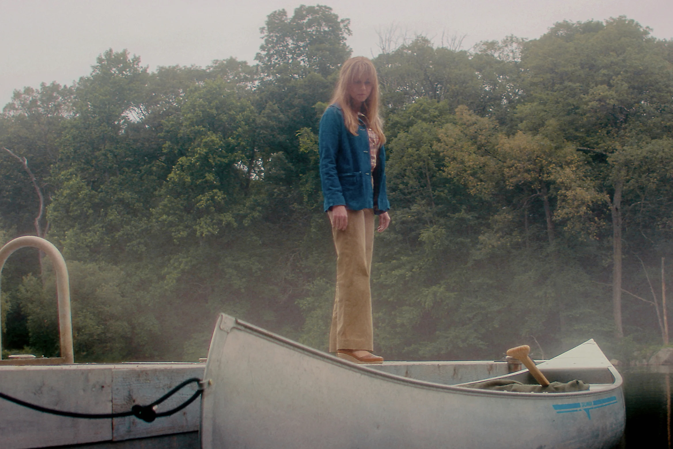 Pamela Voorhees no cais de Crystal Lake, diante da mata e de canoas.