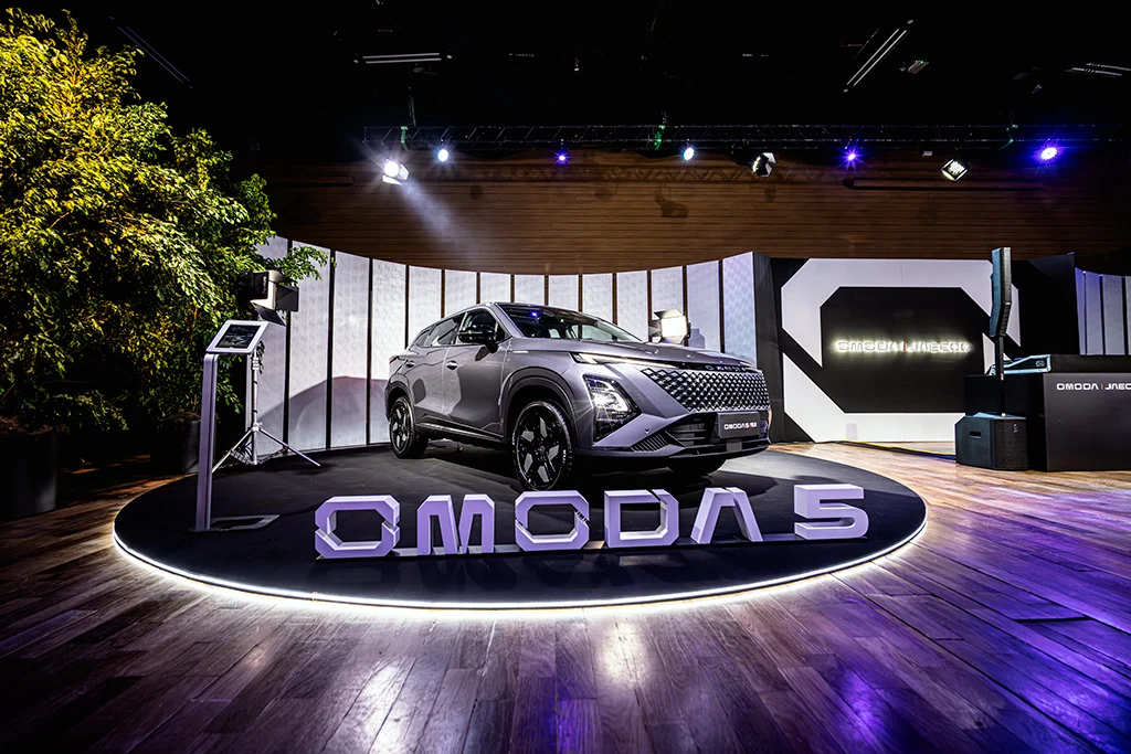 Omoda 5 prateado apresentado em palco de lançamento com iluminação roxa