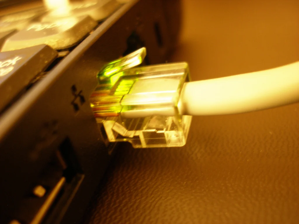 Conector RJ45 de um cabo de rede Ethernet conectado a uma porta de computador