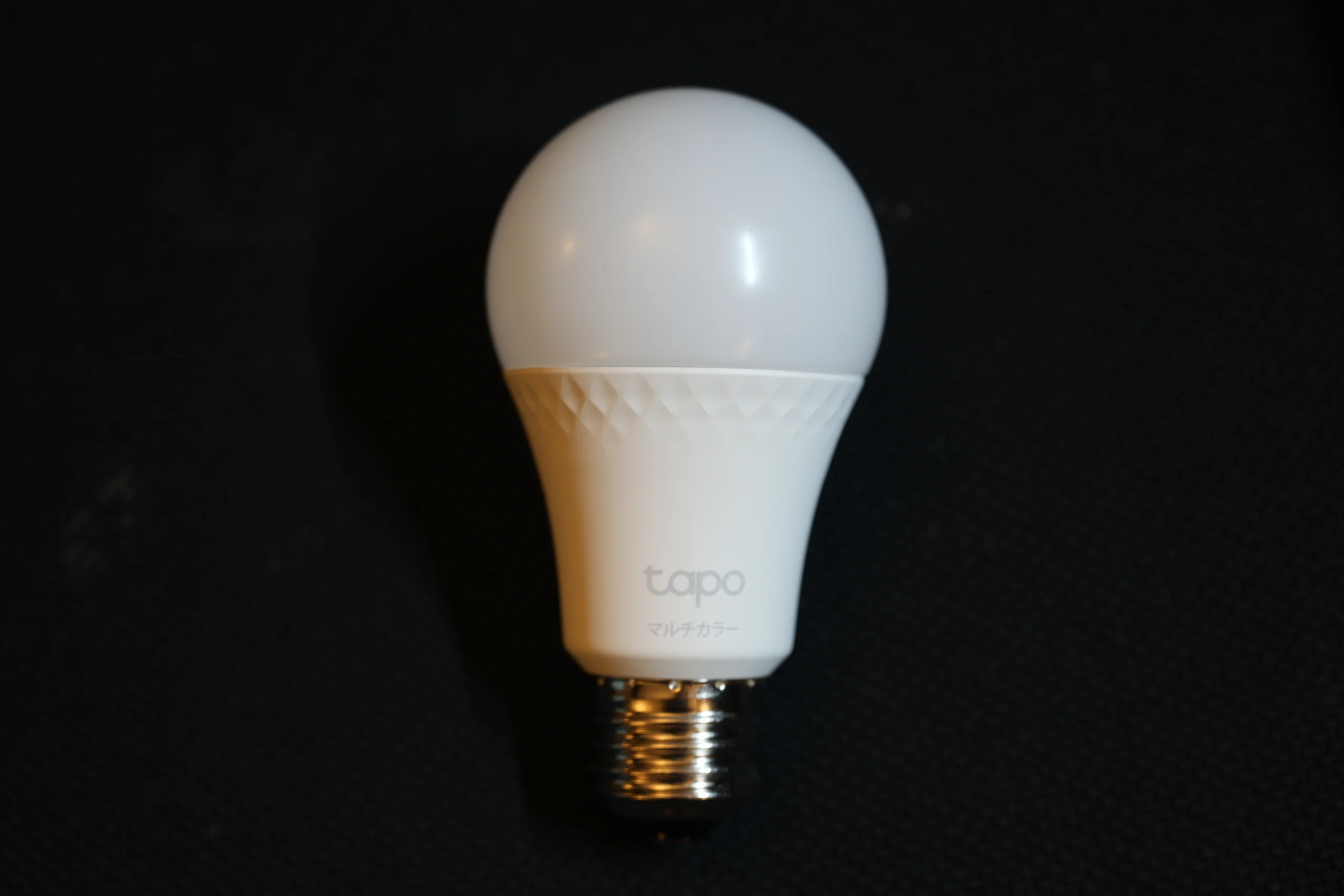 Lâmpada inteligente Tapo fotografada sobre fundo escuro, representando dispositivos de iluminação usados em casas conectadas