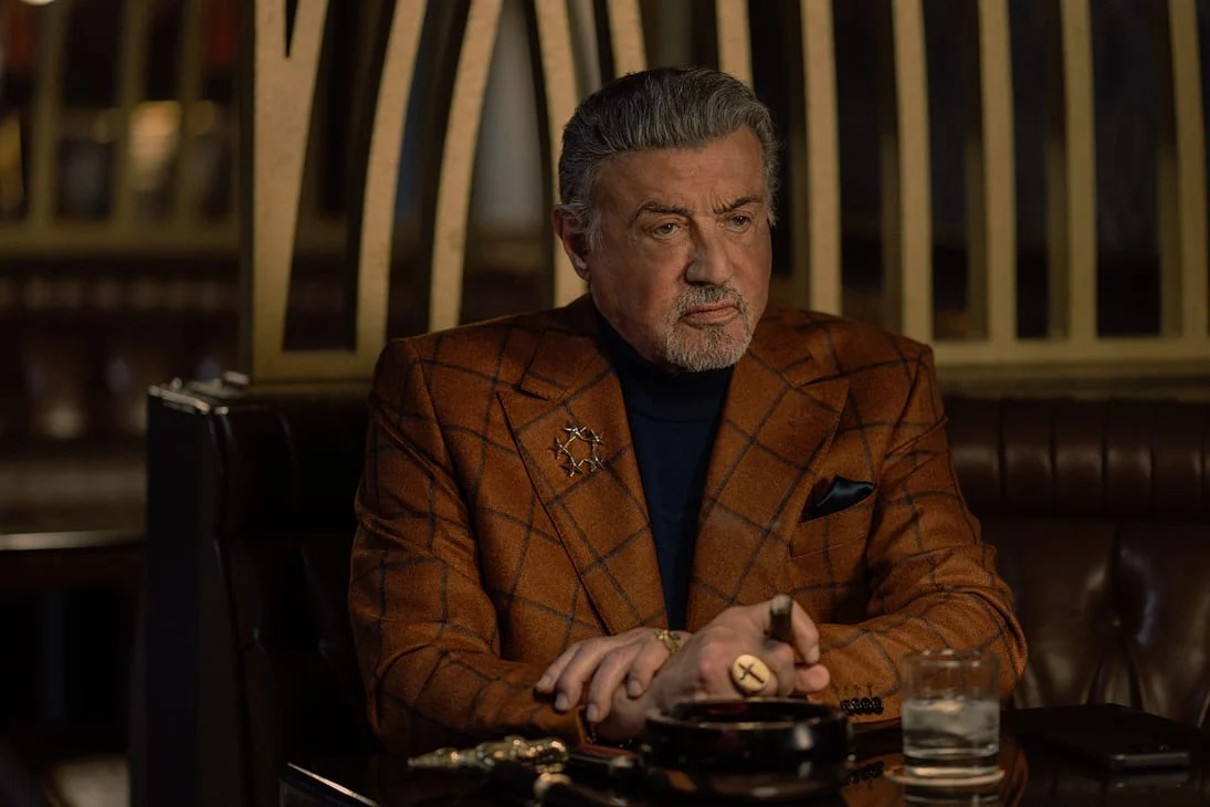 Sylvester Stallone como Dwight Manfredi sentado à mesa na quarta temporada de Tulsa King