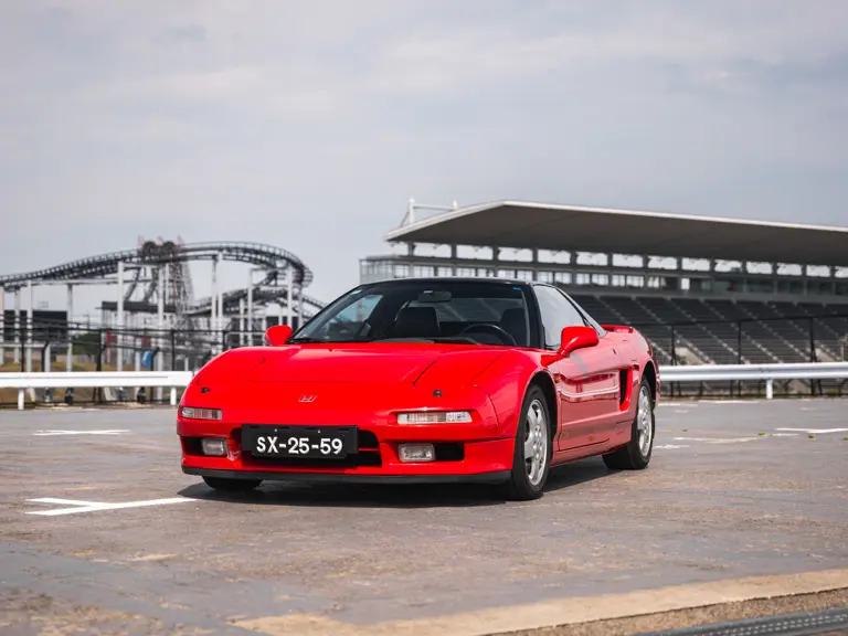 Honda NSX vermelho de 1991 usado por Ayrton Senna, com teto preto e placa portuguesa SX-25-59, fotografado em circuito