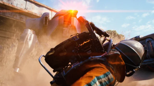 Combatente mira sua arma contra uma máquina ARC em uma área industrial.