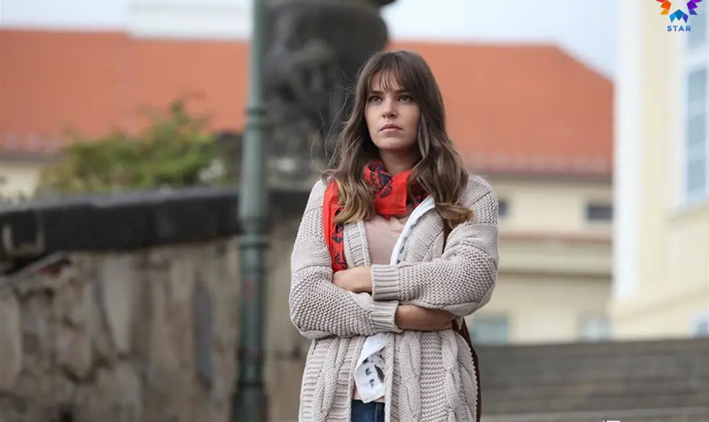 Süreyya de braços cruzados em uma ponte, em imagem do episódio 17 original de Para Sempre no Meu Coração.