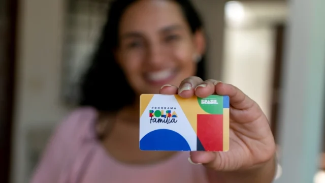 Beneficiária mostra o cartão oficial do programa Bolsa Família