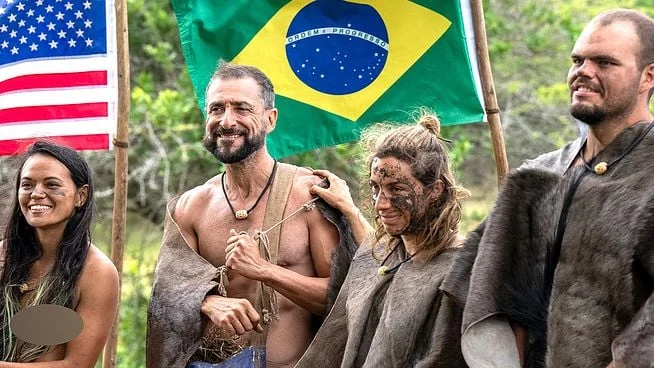 Participantes de Largados e Pelados: Campeões do Mundo reunidos diante das bandeiras dos Estados Unidos e do Brasil