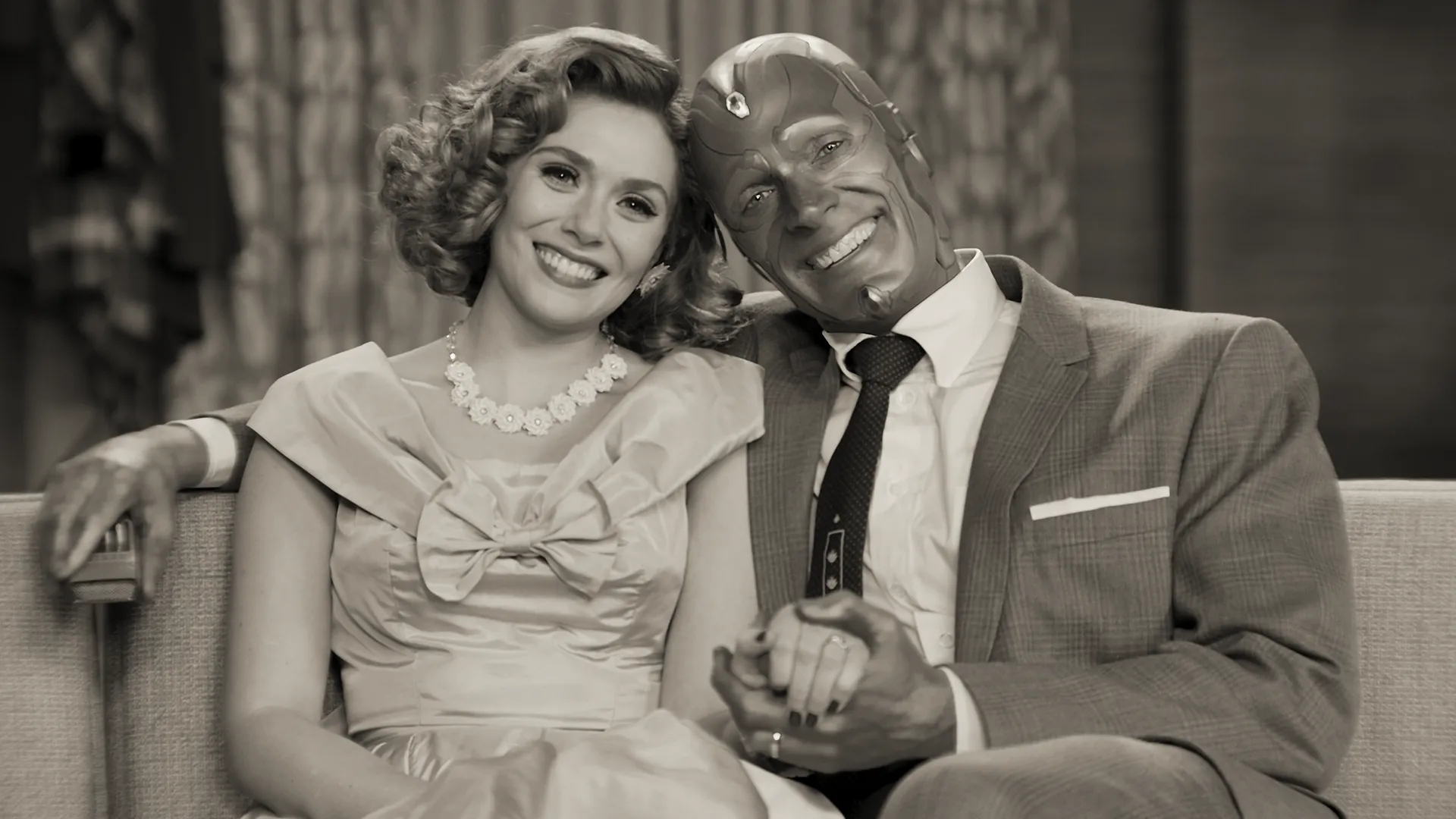 Wanda Maximoff e Visão sorrindo em uma cena em preto e branco inspirada nas comédias clássicas de WandaVision
