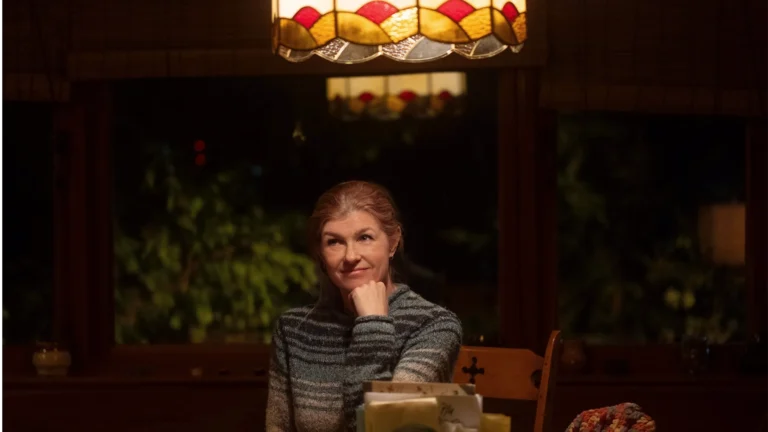 Ellen, interpretada por Connie Britton, está sentada à mesa de casa em uma cena de Fingida