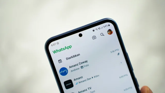 Celular Android com a lista de conversas do WhatsApp aberta sobre um fundo claro