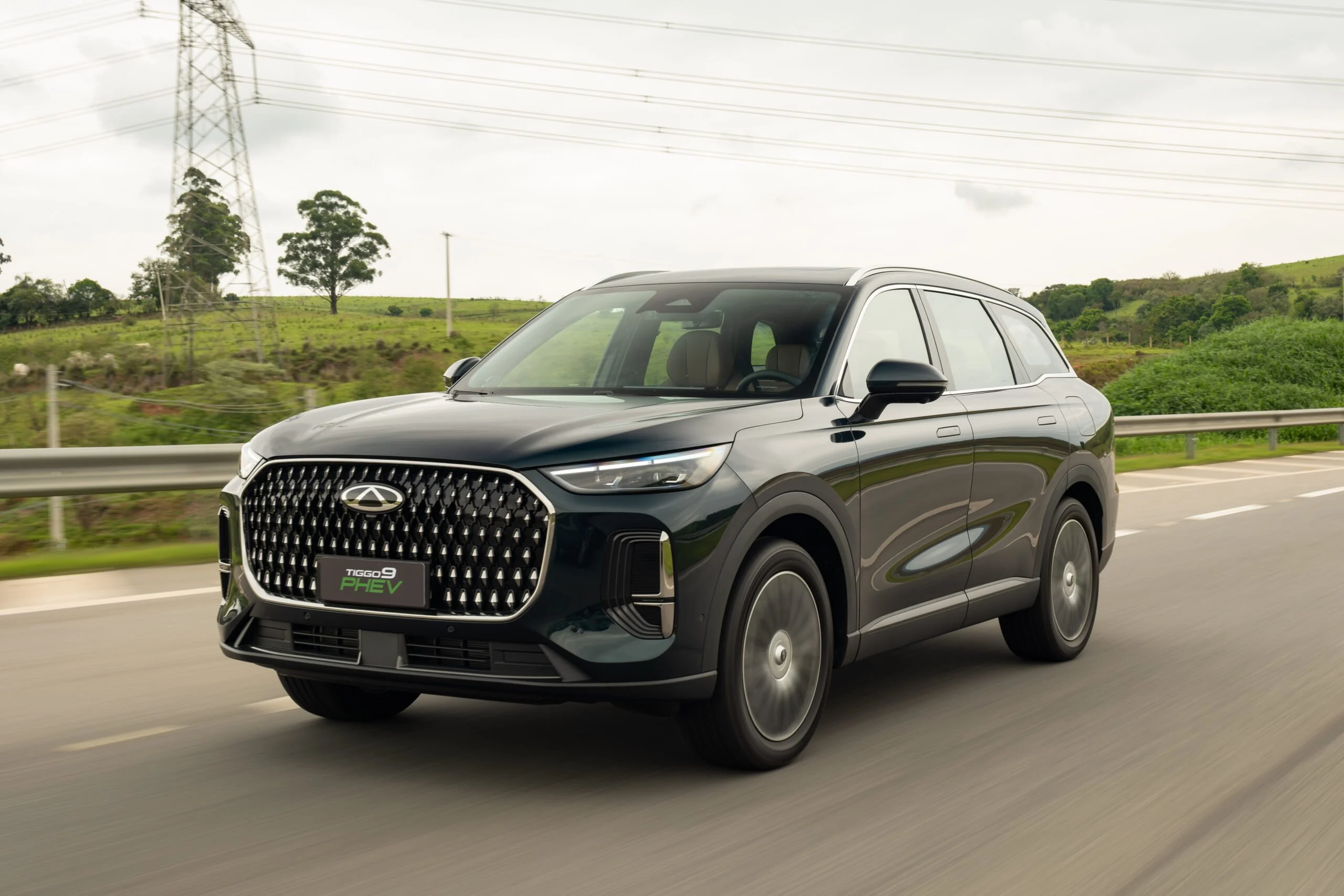 CAOA Chery Tiggo 9 PHEV preto visto de frente e de lado em uma rodovia