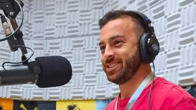 Eduardo Sotto Mayor usa fones de ouvido diante de um microfone no estúdio da Rádio UFSCar.