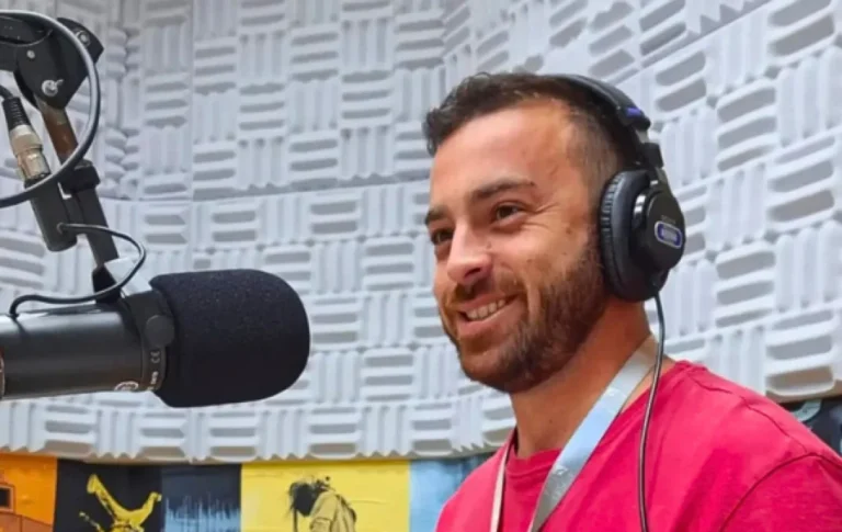 Eduardo Sotto Mayor usa fones de ouvido diante de um microfone no estúdio da Rádio UFSCar.