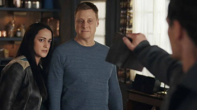 Asta e Harry olham para um homem que segura um livro em Resident Alien.