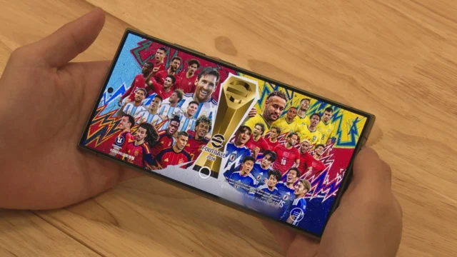 Celular exibindo a tela inicial do eFootball com jogadores de futebol e troféu