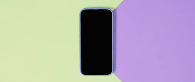 Celular com a tela apagada sobre uma superfície verde e roxa