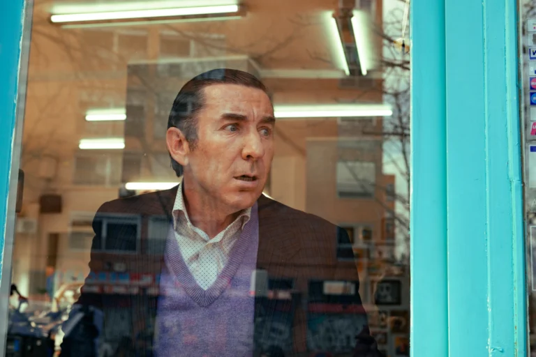 Leandro observa o interior de um estabelecimento através da vitrine.