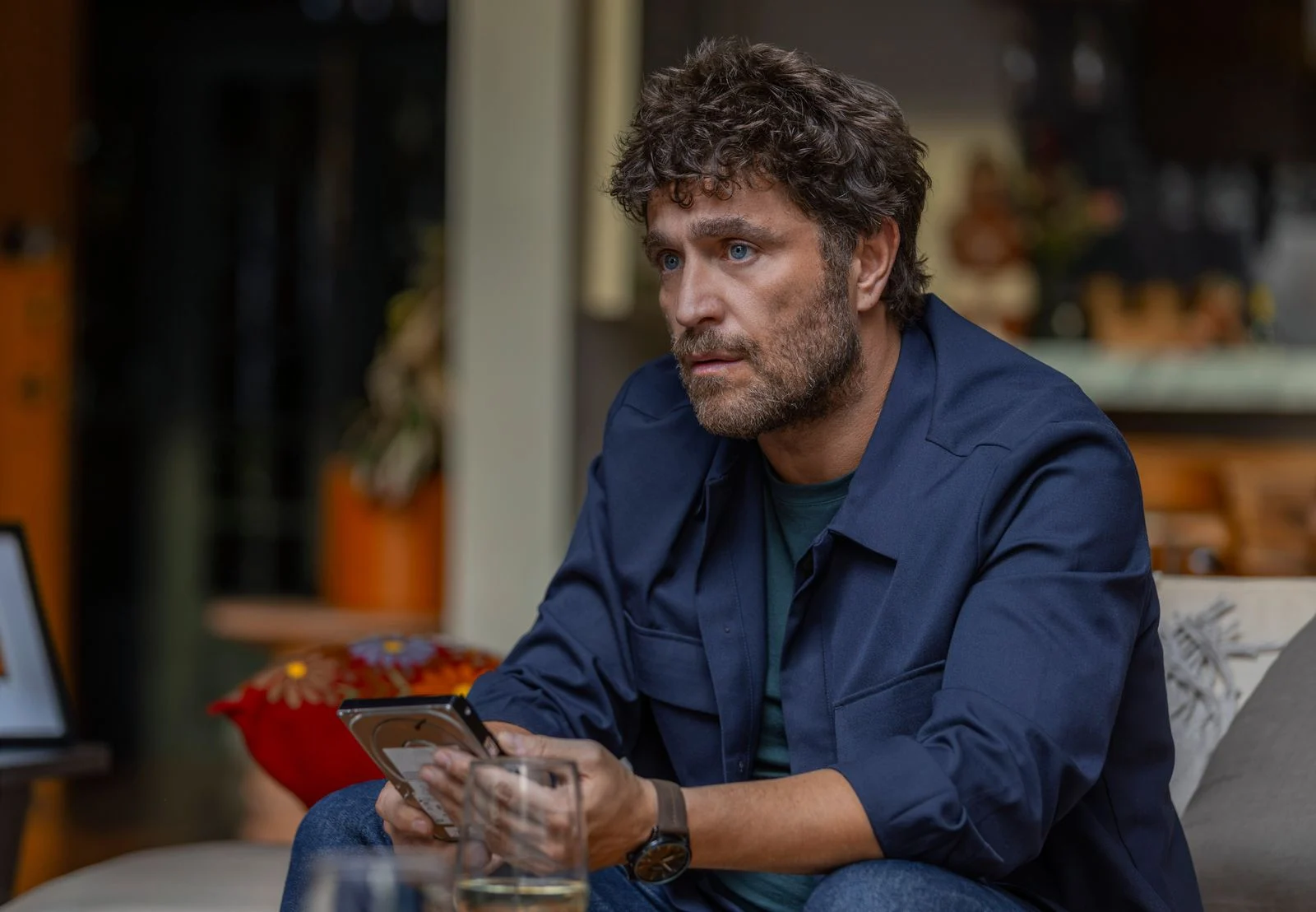 Michel Brown como Tomás Arizmendi, sentado e segurando um celular em Dentro do Círculo