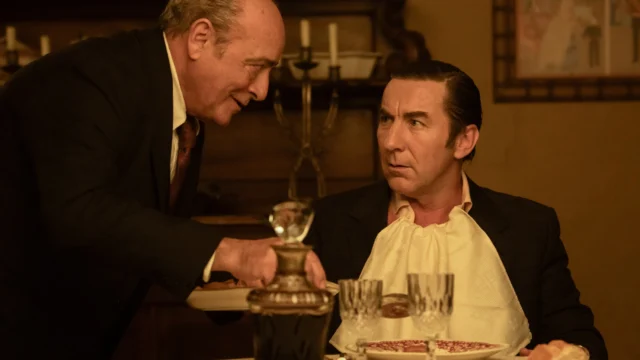 Leandro e um homem mais velho conversam à mesa durante uma refeição.