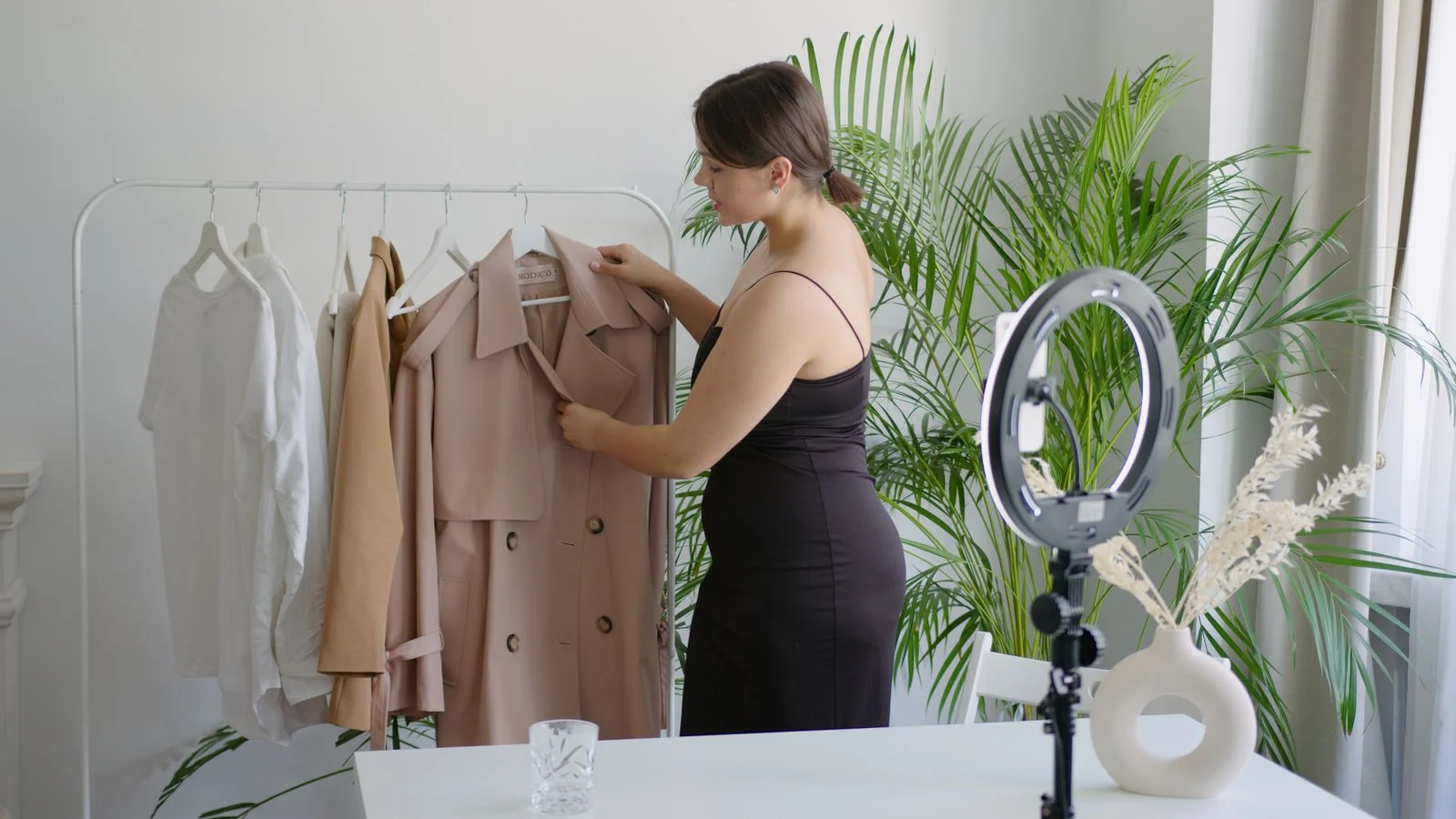 Criadora organiza roupas em um cenário de vendas online com iluminação para vídeo