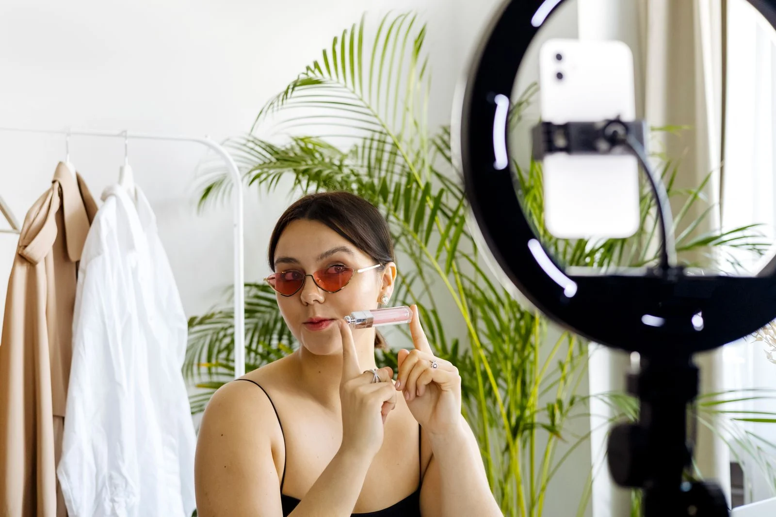 Criadora de conteúdo apresenta um produto cosmético diante de um smartphone e iluminação circular
