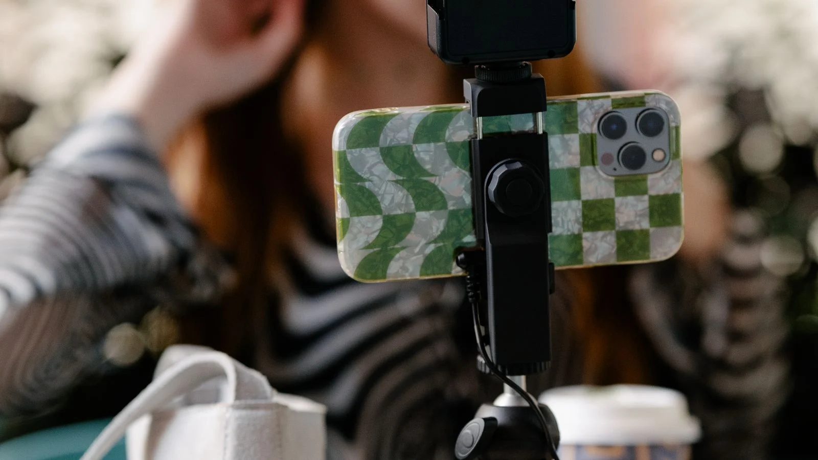 Criadora de conteúdo produz vídeo diante de celular apoiado em tripé