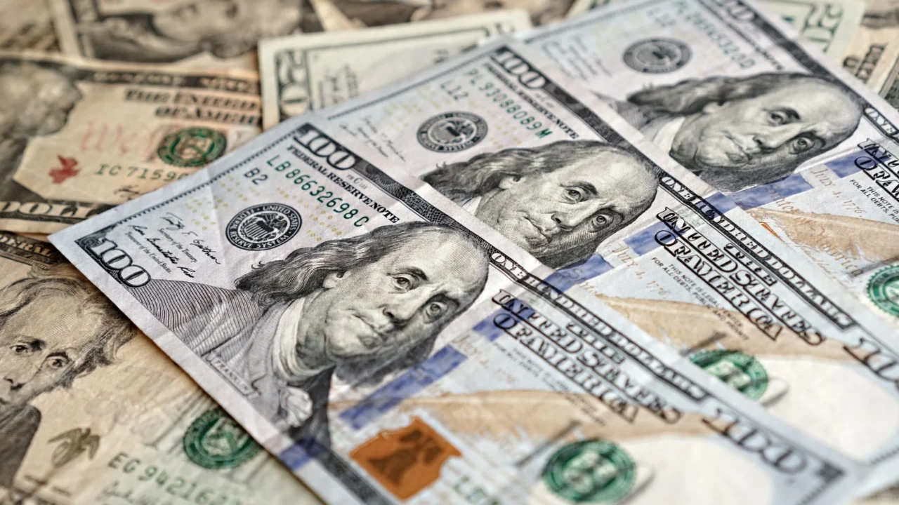 Notas de cem dólares espalhadas sobre uma superfície, em fotografia ilustrativa da cotação do dólar