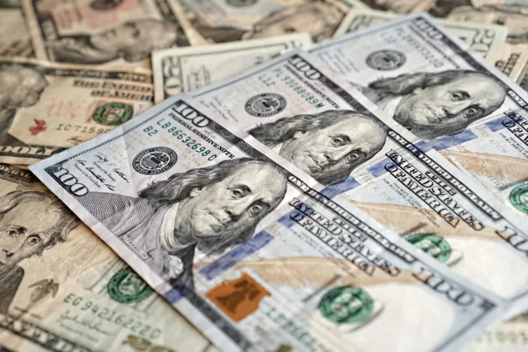 Notas de cem dólares espalhadas sobre uma superfície, em fotografia ilustrativa da cotação do dólar