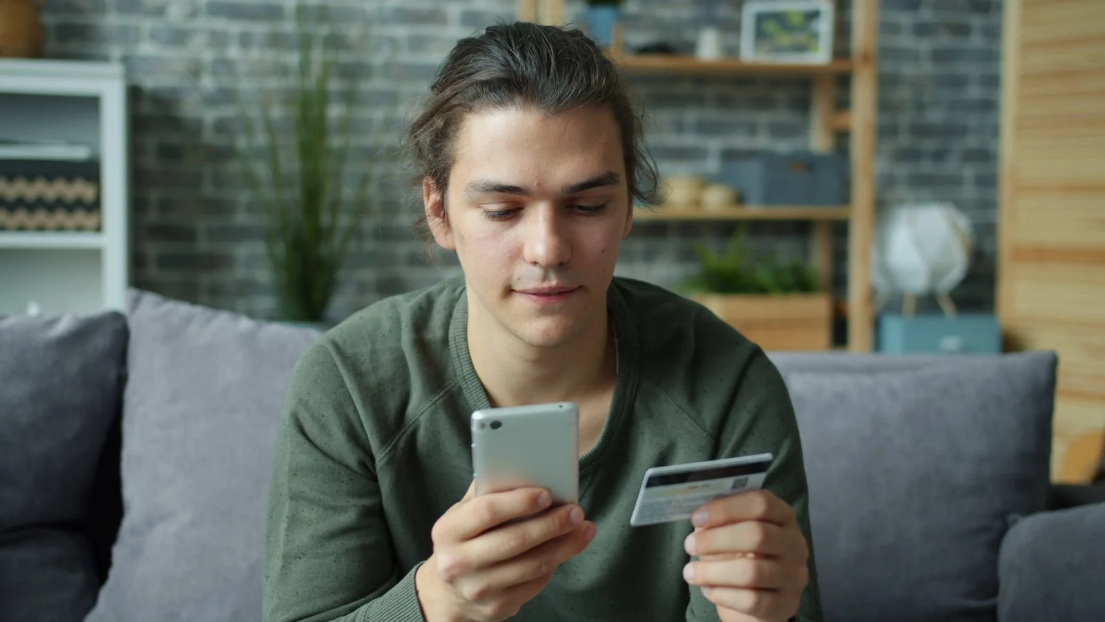 Pessoa usando celular e cartão para fazer uma compra online