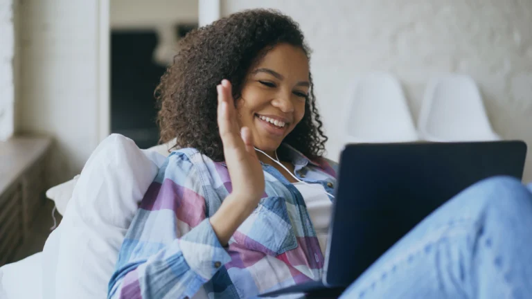 Mulher com fones de ouvido em videochamada pelo notebook, formato utilizado por cursos de inglês online