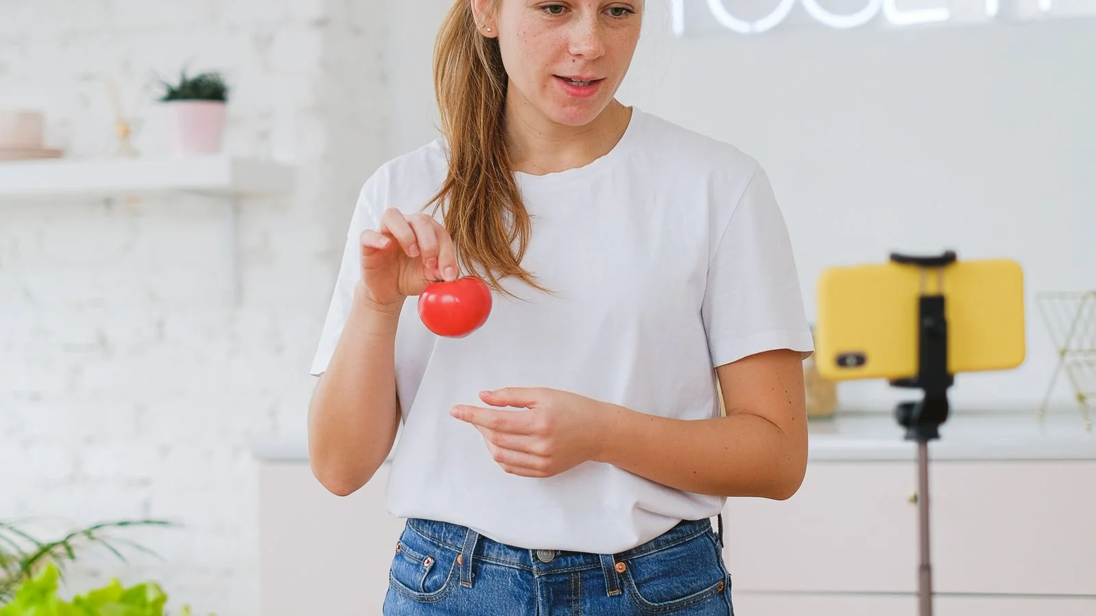 Criadora grava conteúdo de culinária com smartphone e tripé em uma cozinha