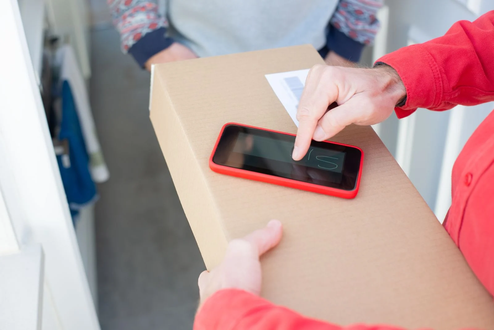 Smartphone ao lado de uma caixa de encomenda, representando o acompanhamento de uma entrega