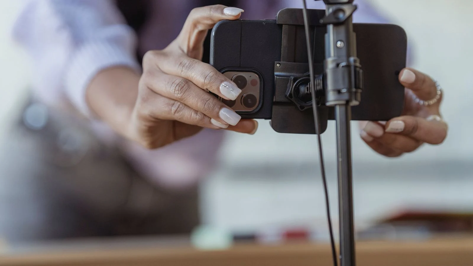 Pessoa ajusta um smartphone em tripé para gravar vídeo de conteúdo digital