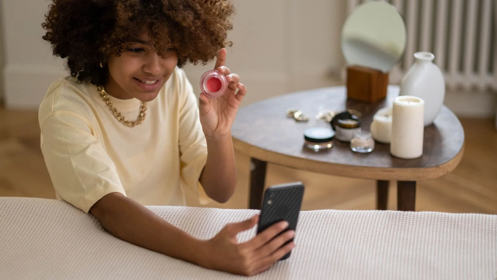 Criadora mostrando produto de beleza enquanto grava vídeo com smartphone