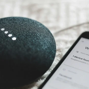 Google Home Mini ao lado de um smartphone com aplicativo de controle da casa