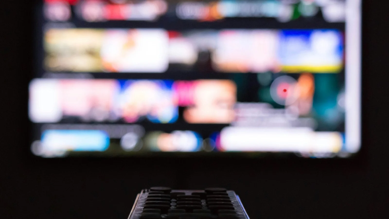 Controle remoto sobre superfície diante de uma televisão, ilustrando o uso de uma TV antiga