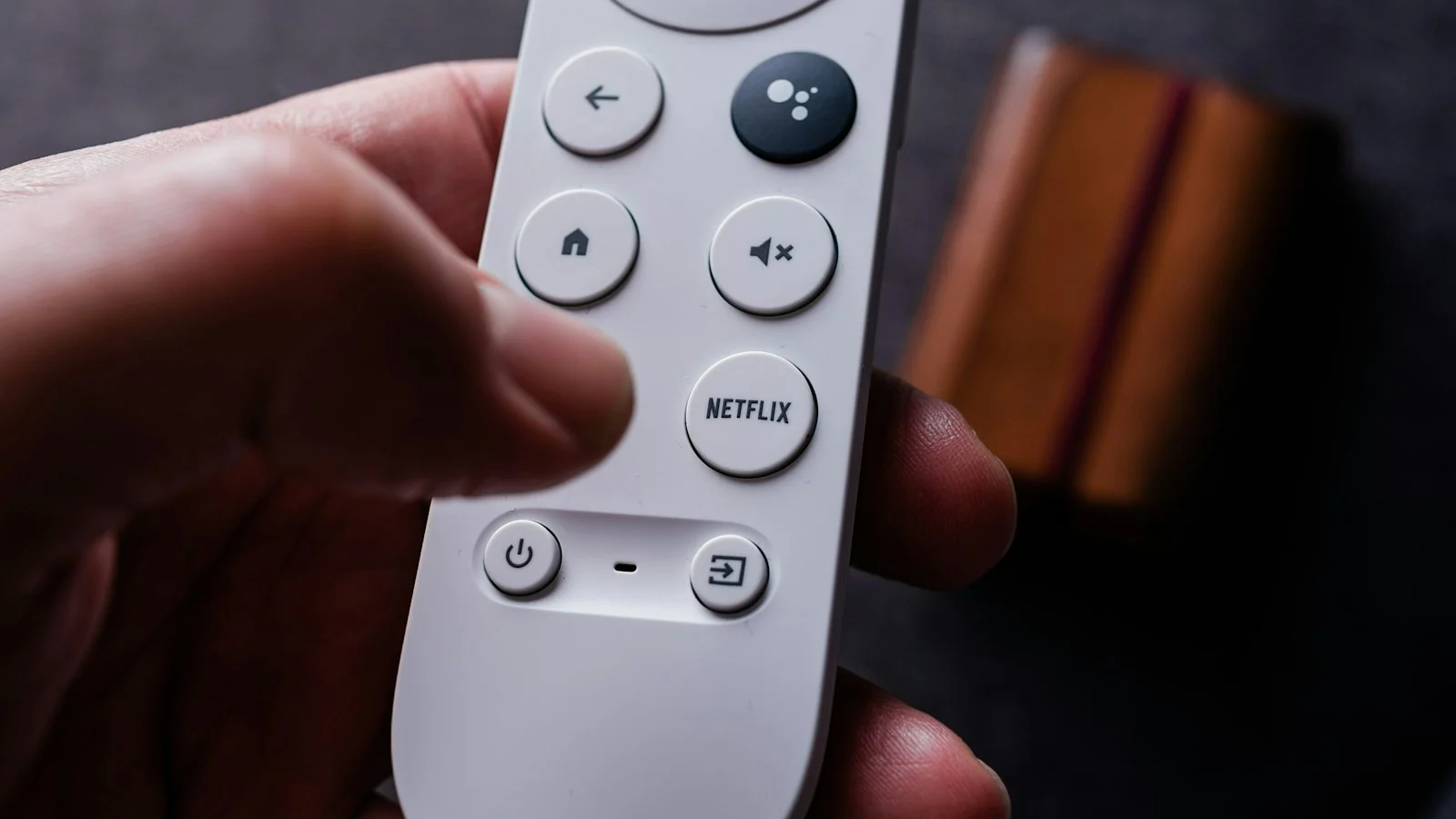 Mão segurando controle remoto com botão da Netflix em destaque