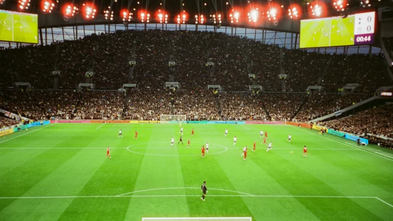 Campo de futebol visto da arquibancada de um estádio com torcedores