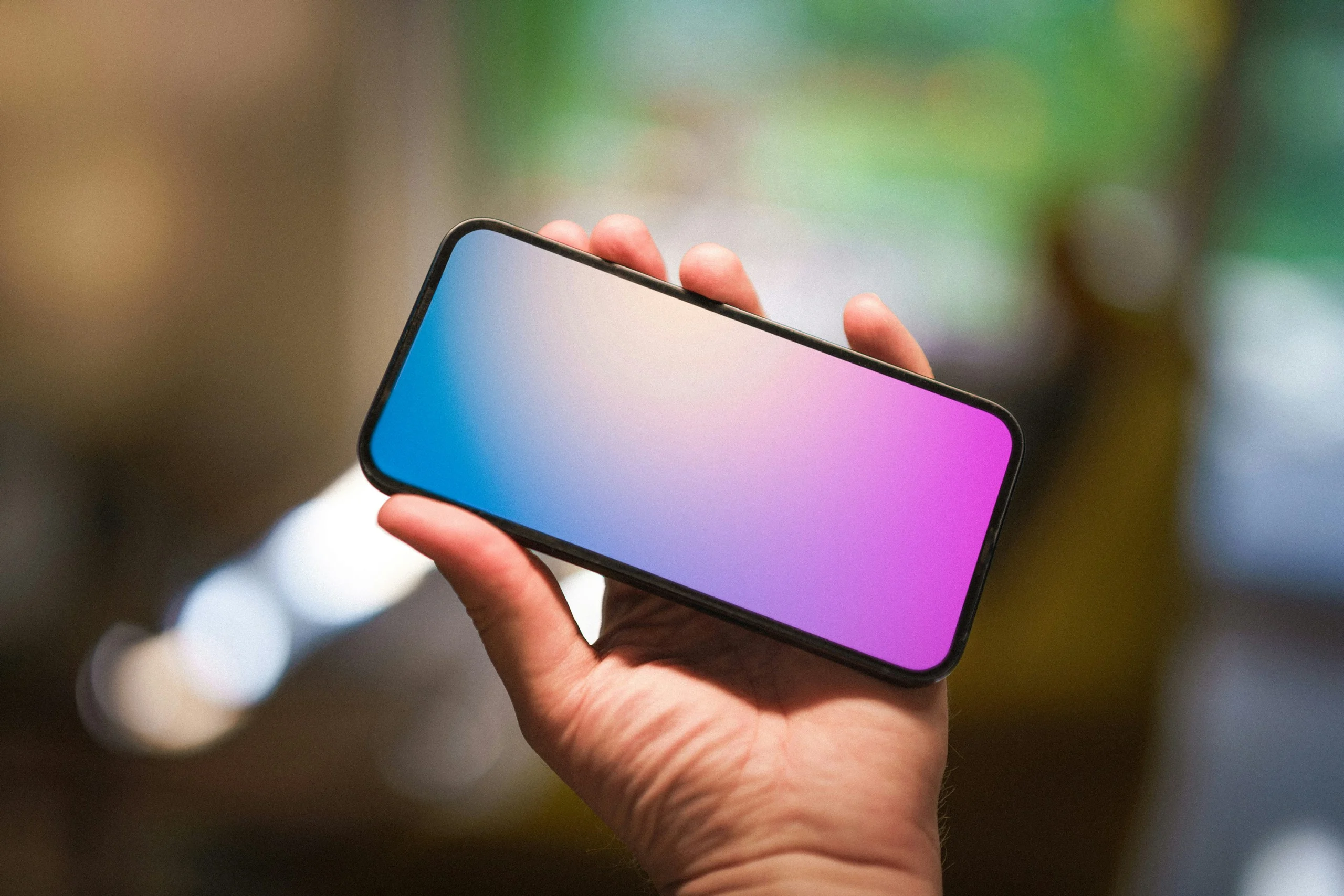 Mão segurando celular com tela em tons de azul e rosa; foto ilustrativa sobre redes sociais para adultos