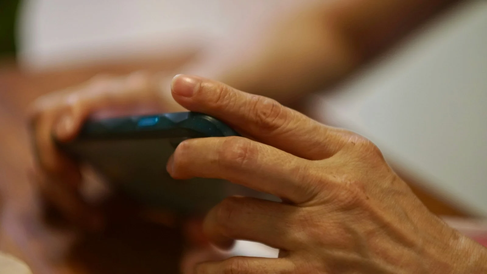 Mãos seguram celular na horizontal durante partida de jogo mobile