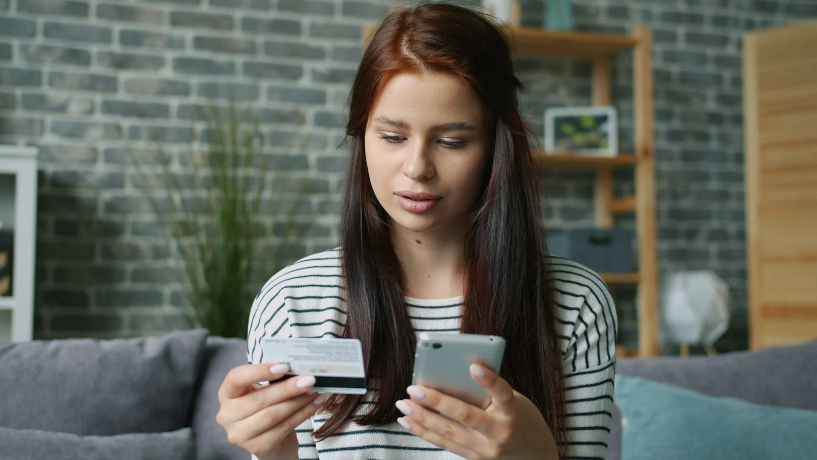 Consumidora com smartphone e cartão bancário durante uma compra pela internet