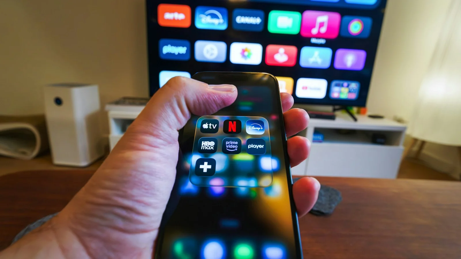 Celular com aplicativos de streaming, incluindo Netflix e HBO Max, diante de uma Smart TV