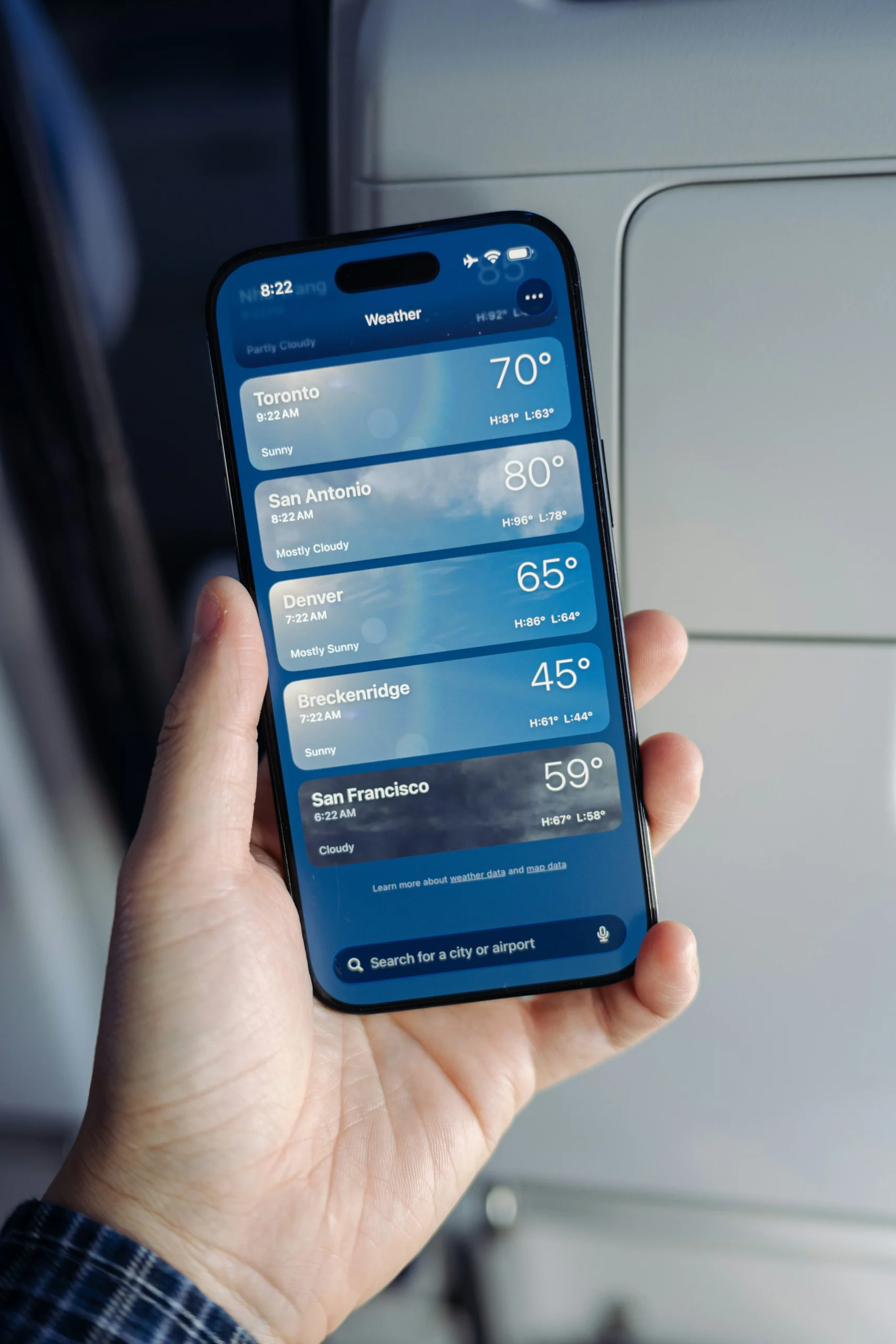 Celular exibindo temperaturas e previsão do tempo de diferentes localidades