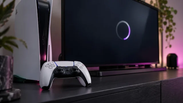 Ilustração de um PS5 e DualSense diante de uma tela com círculo de carregamento