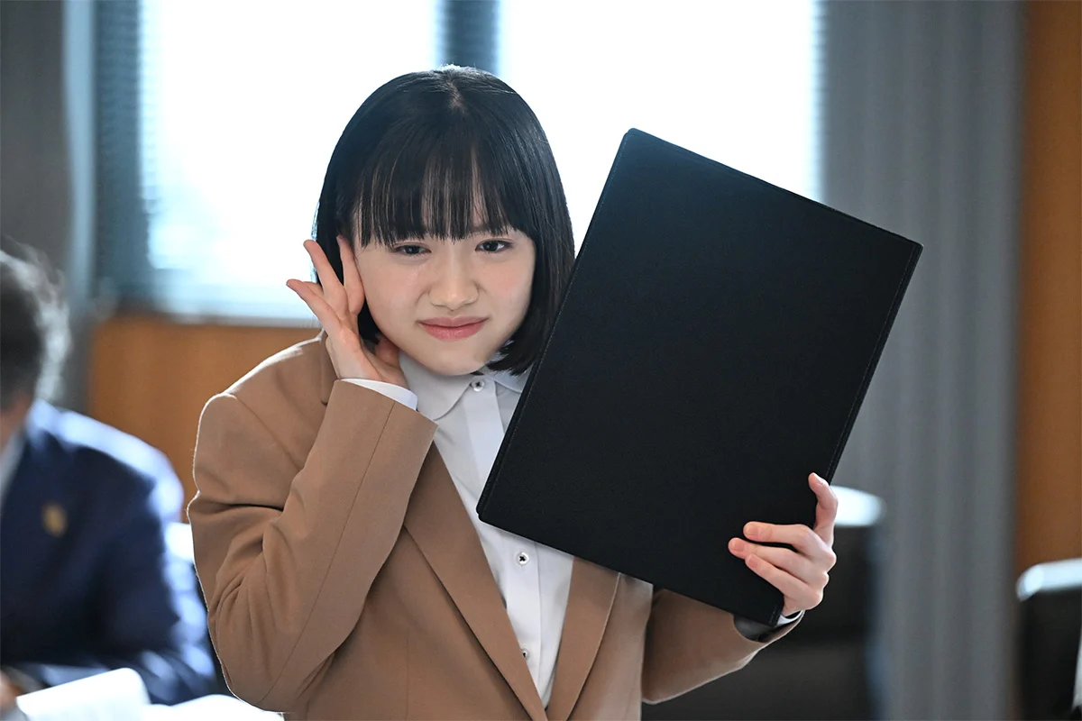 Mana Ashida como Minami Minamida, segurando uma pasta em cena da série japonesa
