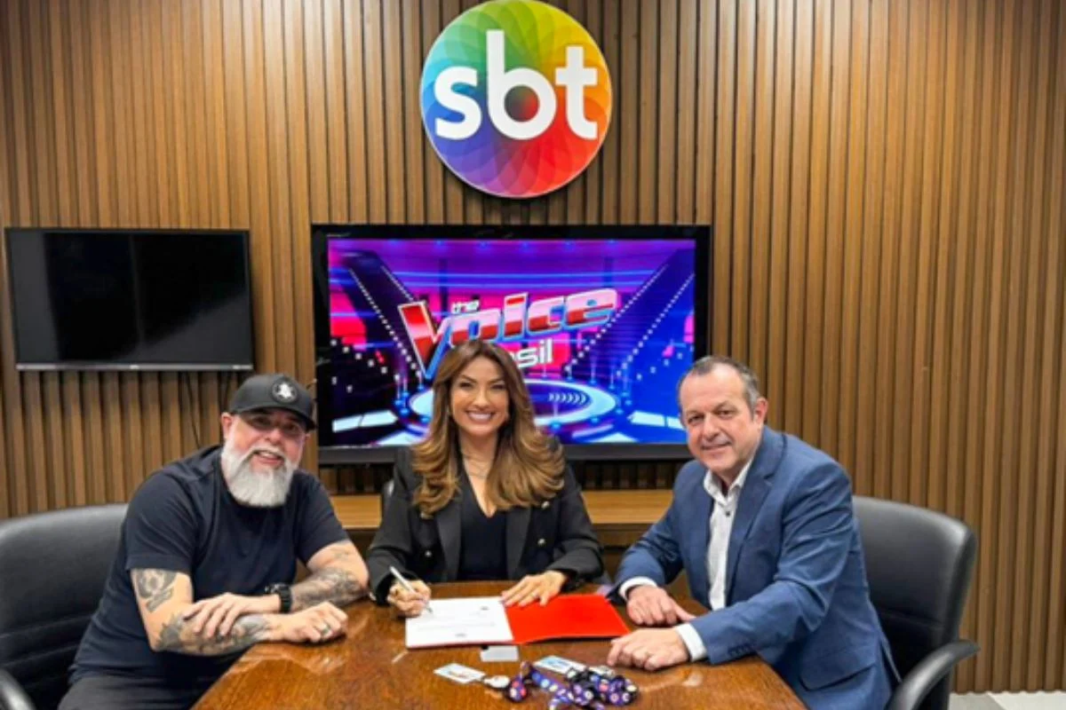 Thayse Teixeira assina contrato com o SBT, sentada à mesa entre Márcio Esquilo e Mauro Lissoni